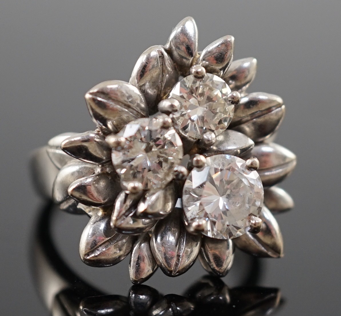 An 18ct white gold and three stone diamond set flowerhead ring